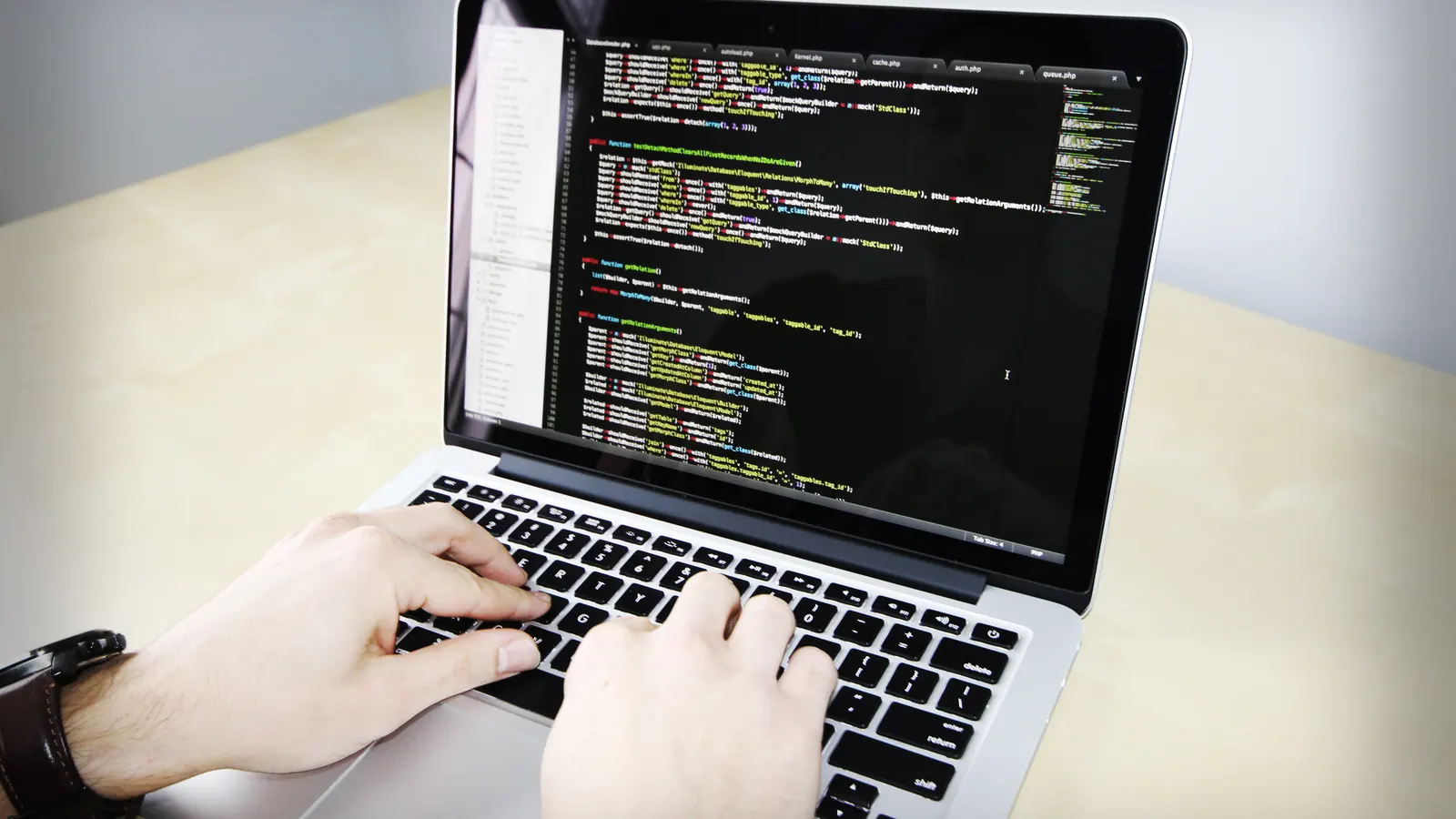 Hands typing code on a laptop