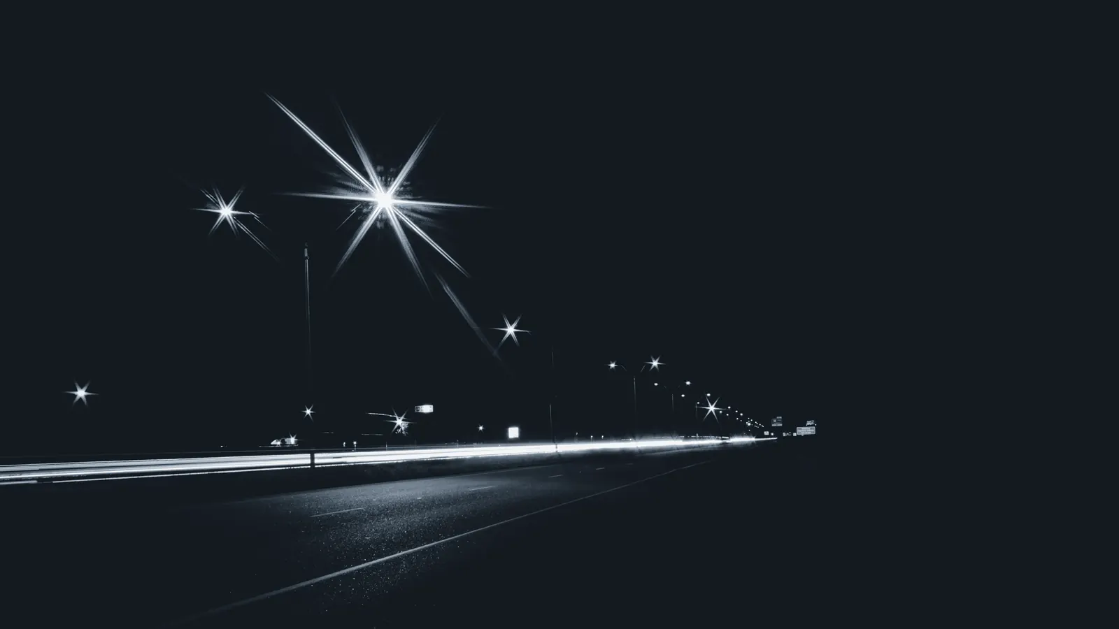 Light streaks along a dark road at night